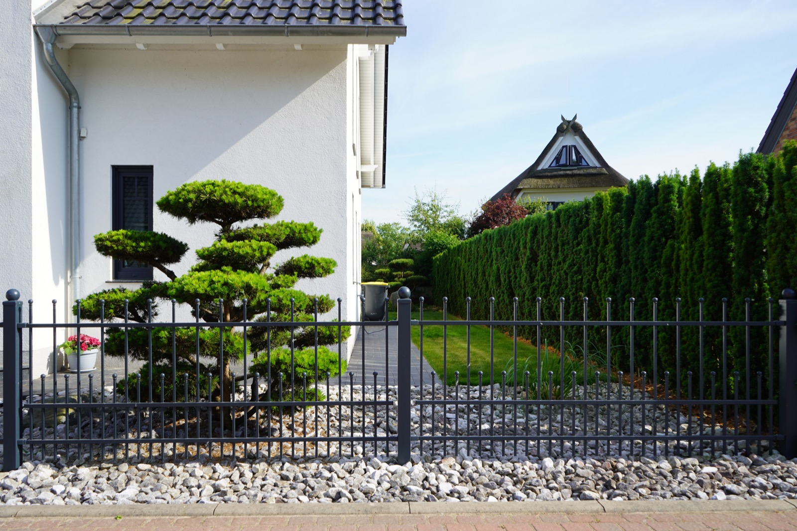 Klassischer Zaun mit Kugelspitzen und Bonsai
