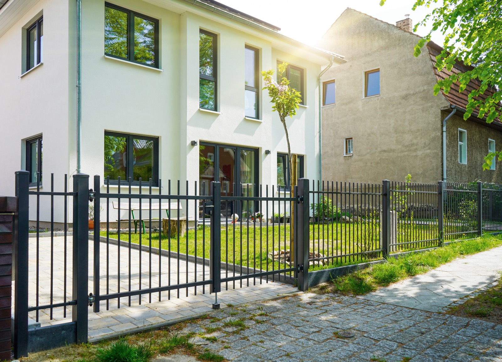 Klassischer Stabzaun mit Pforte vor weißem Haus